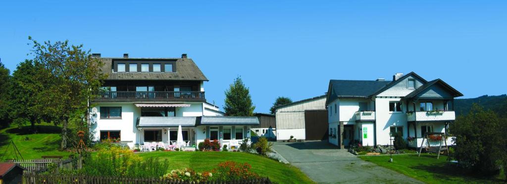 une grande maison avec un jardin en face de celle-ci dans l'établissement Bauernhofpension Hof Dödesberg, à Bad Berleburg