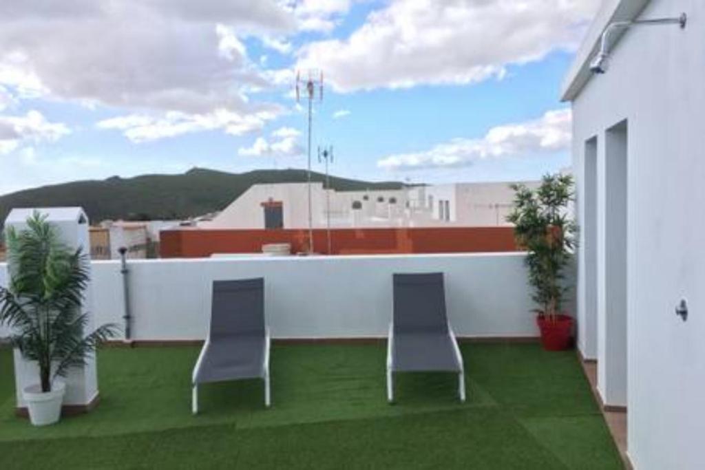 2 stoelen op een balkon met groen gras bij Apartamentos cerca del Aeropuerto in Ingenio