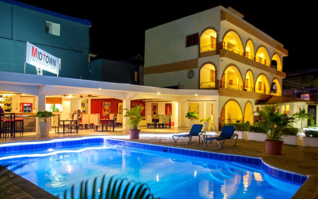 uma piscina em frente a um hotel à noite em Hotel Las Palmeras em Sosúa