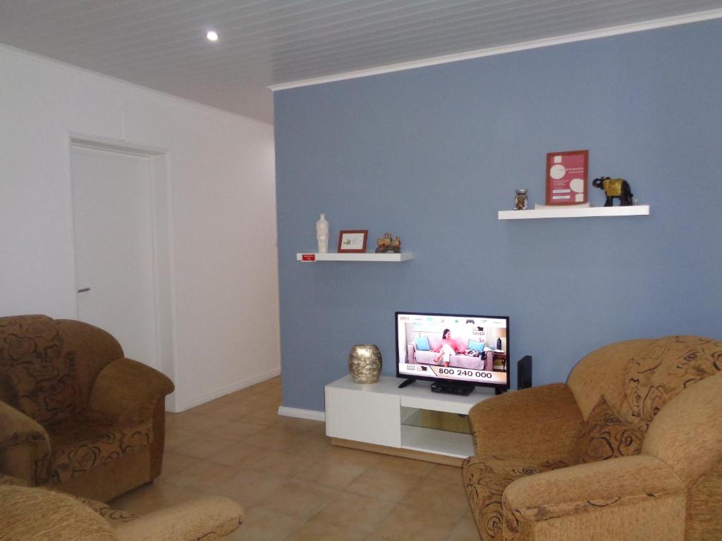 a living room with two chairs and a flat screen tv at Apartamento do Barao in Ponta Delgada