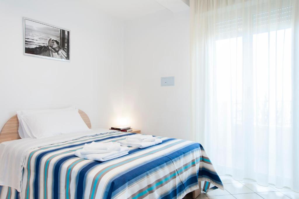 a bedroom with a bed with a blue and white striped blanket at Residence Cigno in Rimini