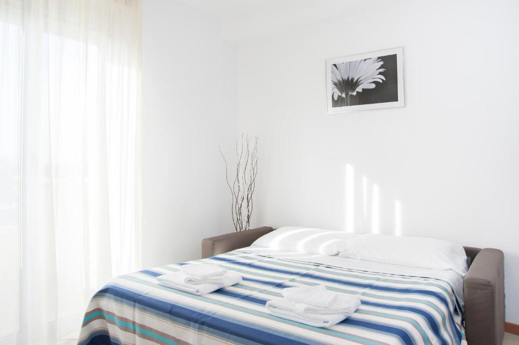 a white bedroom with a bed with towels on it at Residence Cigno in Rimini