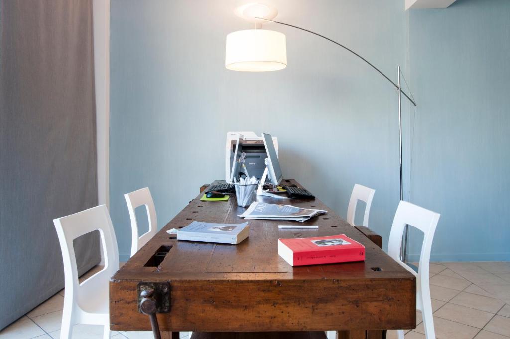 a wooden table with white chairs and a lamp at Residence Cigno in Rimini