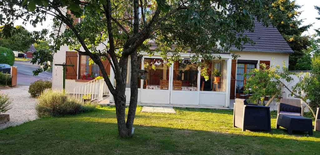 une maison avec un arbre dans la cour dans l'établissement gite du luat, à Vert-en-Drouais