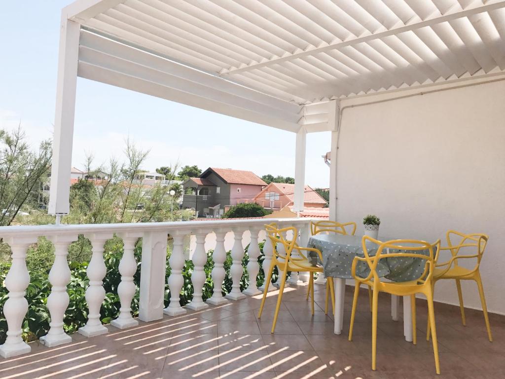 a patio with yellow chairs and a table on a balcony at Vila Virago in Vir