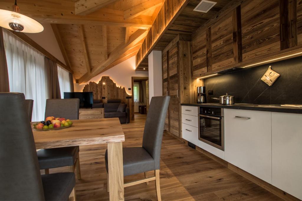 Una cocina y un comedor con mesa y sillas de madera. en Lüch dl Cajer - Appartement Gran crëp, en San Martino in Badia
