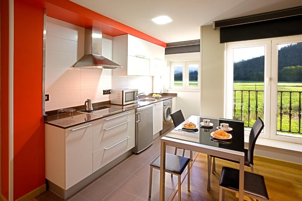 a kitchen with a table and a dining room at Apartamentos Spa Villa Pasiega in Hoznayo