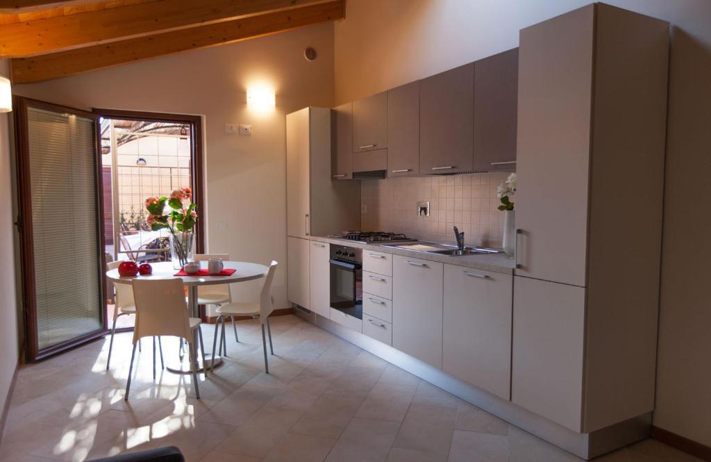 une cuisine avec des placards blancs et une table avec des chaises dans l'établissement "La Terrazza di Castiglione" APPARTAMENTI VACANZA, à Castiglione della Pescaia