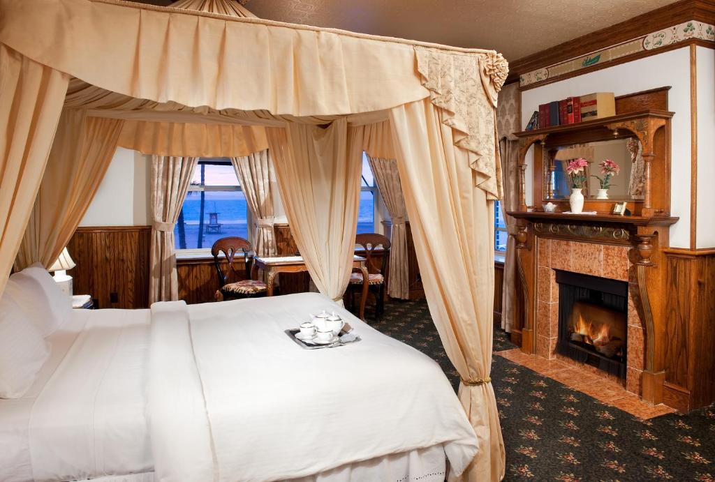 Doryman's Oceanfront Inn في شاطئ نيوبورت: غرفة نوم مع سرير المظلة ومدفأة