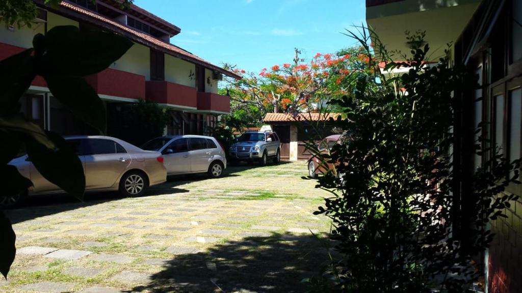 un estacionamiento con autos estacionados al lado de un edificio en Casa completa em Peró!, en Cabo Frío