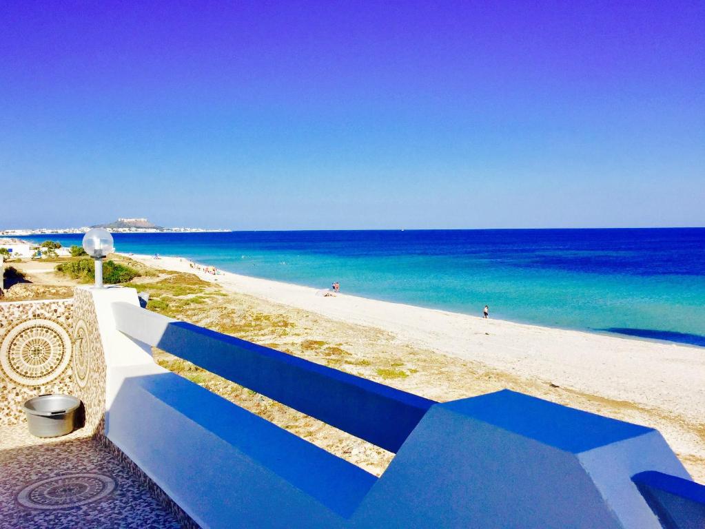 un banco azul junto a una playa con el océano en Casa del Mar Residence, en Kelibia