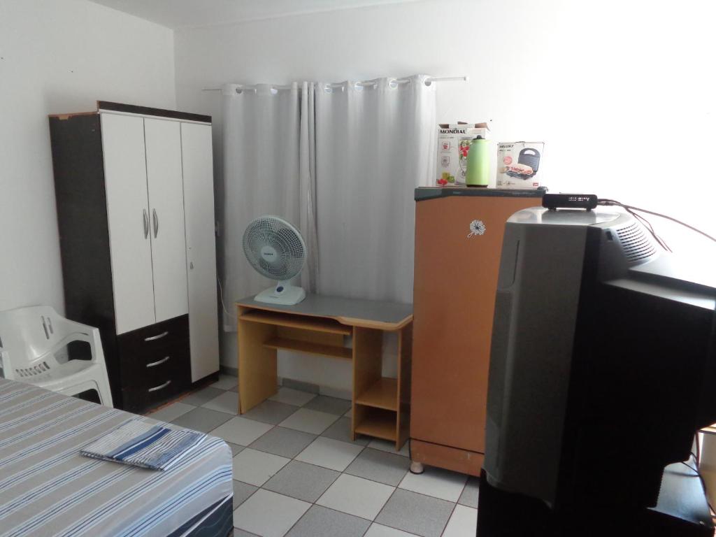 a room with a bed and a desk and a refrigerator at FARO FINO 104 DISNEY in Goiânia