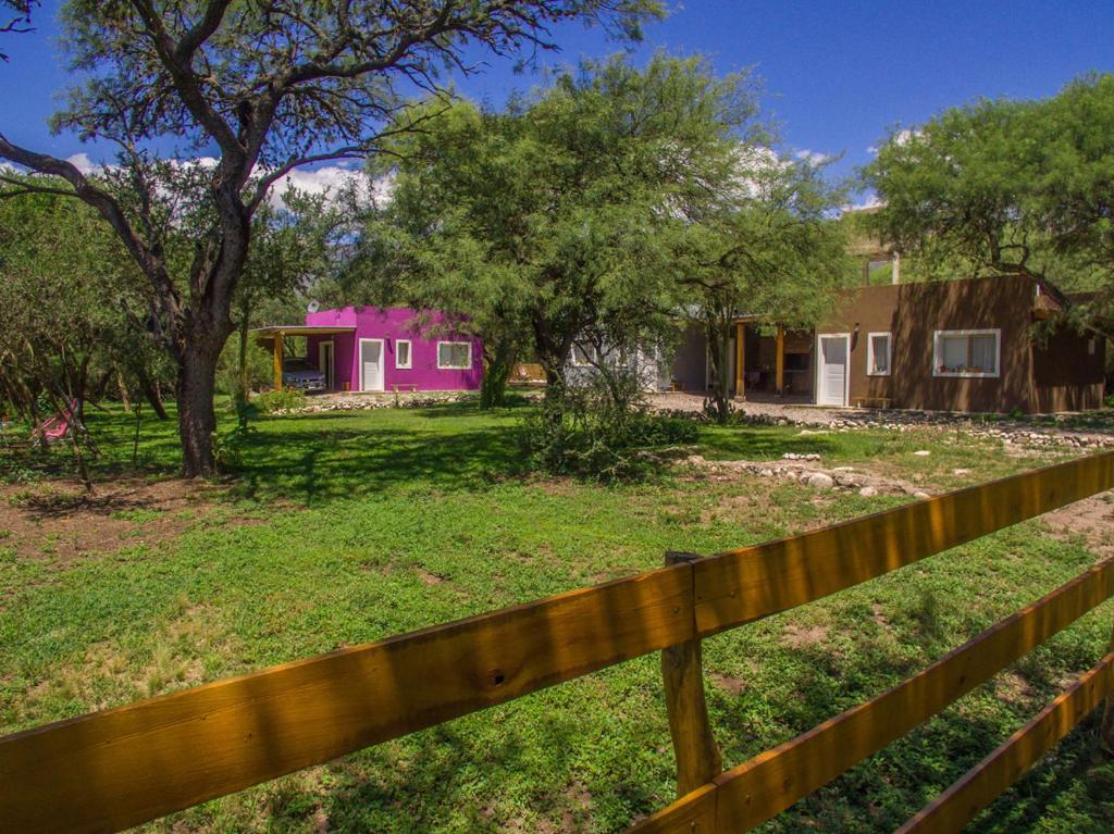a fence in front of a yard with a pink house at Entre Sierras y Pajaros in Las Rabonas
