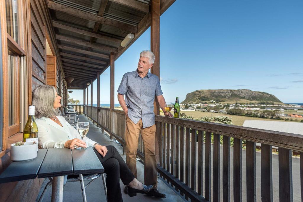 mężczyzna i kobieta stojący na balkonie domu w obiekcie Stanley Seaview Inn w mieście Stanley