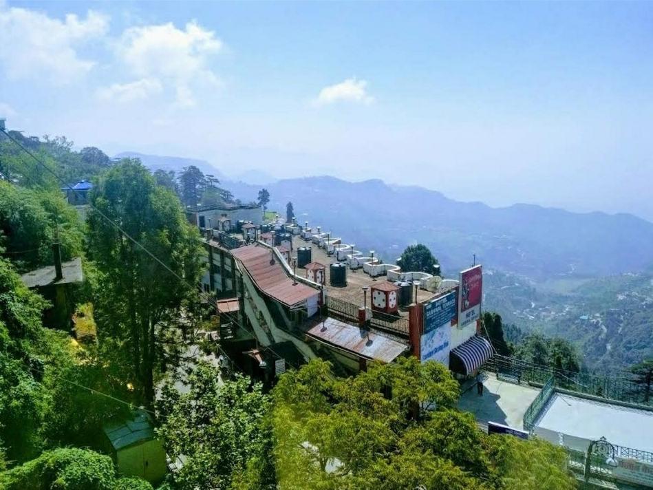 a town on a hill with mountains in the background at The Three Oaks Boutique Hotel in Mussoorie