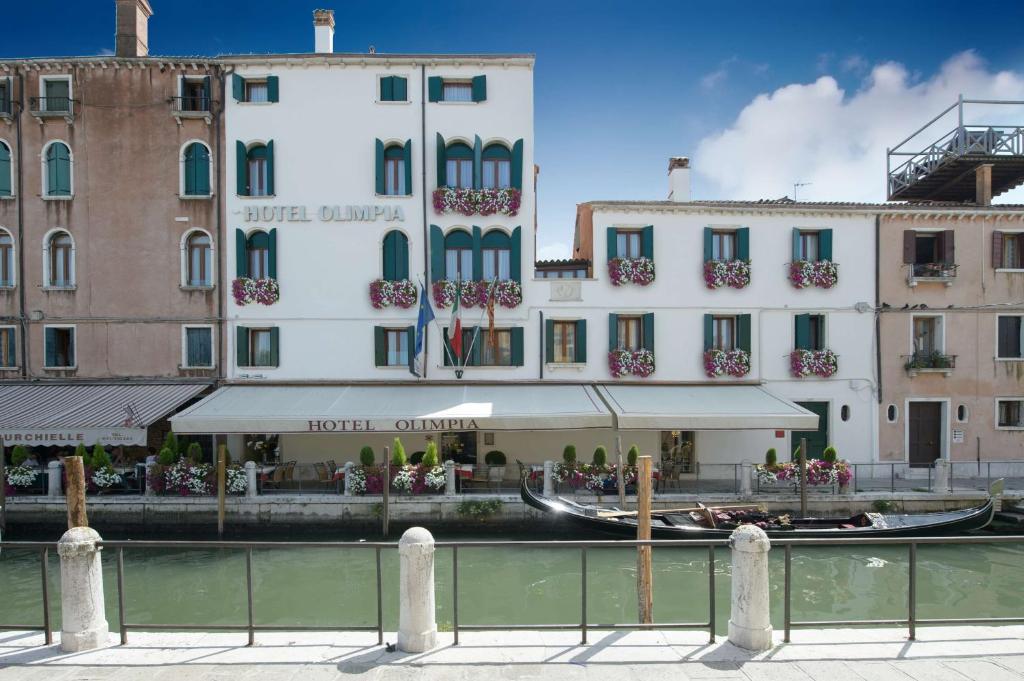 a hotel with a gondola in the water next to buildings at Hotel Olimpia Venice, BW Signature Collection in Venice