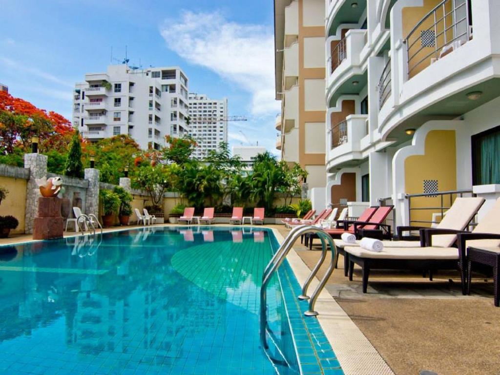 una piscina con sillas y un edificio en Best Beach Villa, en Pattaya central