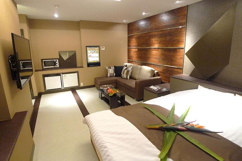 pokój hotelowy z łóżkiem i kanapą w obiekcie Hotel GOLF Nirasaki (Adult Only) w mieście Nirasaki
