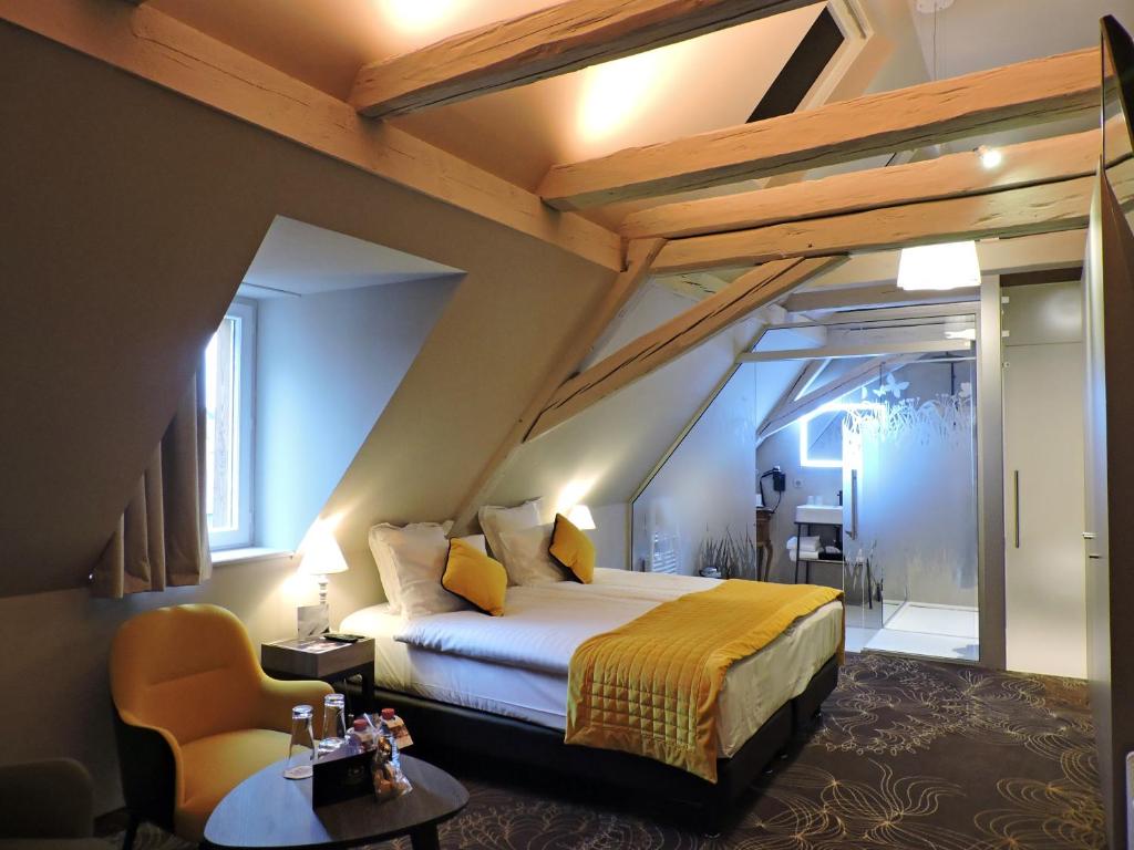 een slaapkamer met een bed, een tafel en een stoel bij Hotel La Couronne in Ensisheim