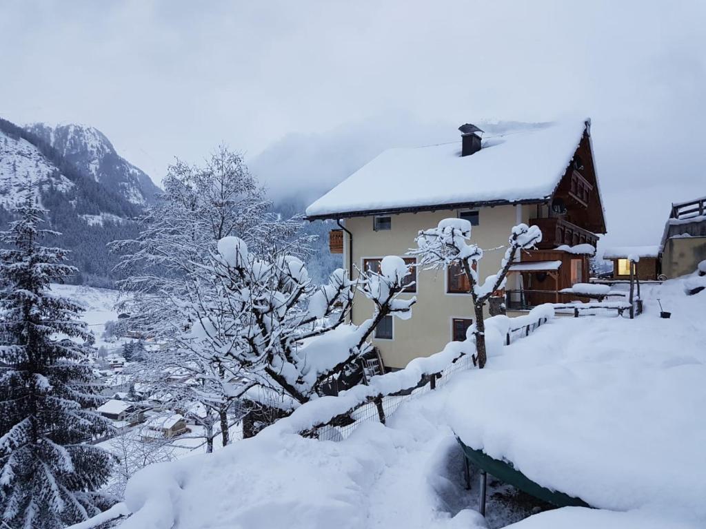 a house covered in snow next to a fence at Appartementhaus Gastein / Haus Sammie in Bad Gastein