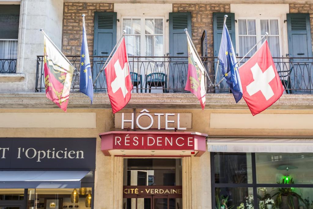 un hotel con banderas en la parte superior de un edificio en Hôtel Résidence Cité-Verdaine, en Ginebra