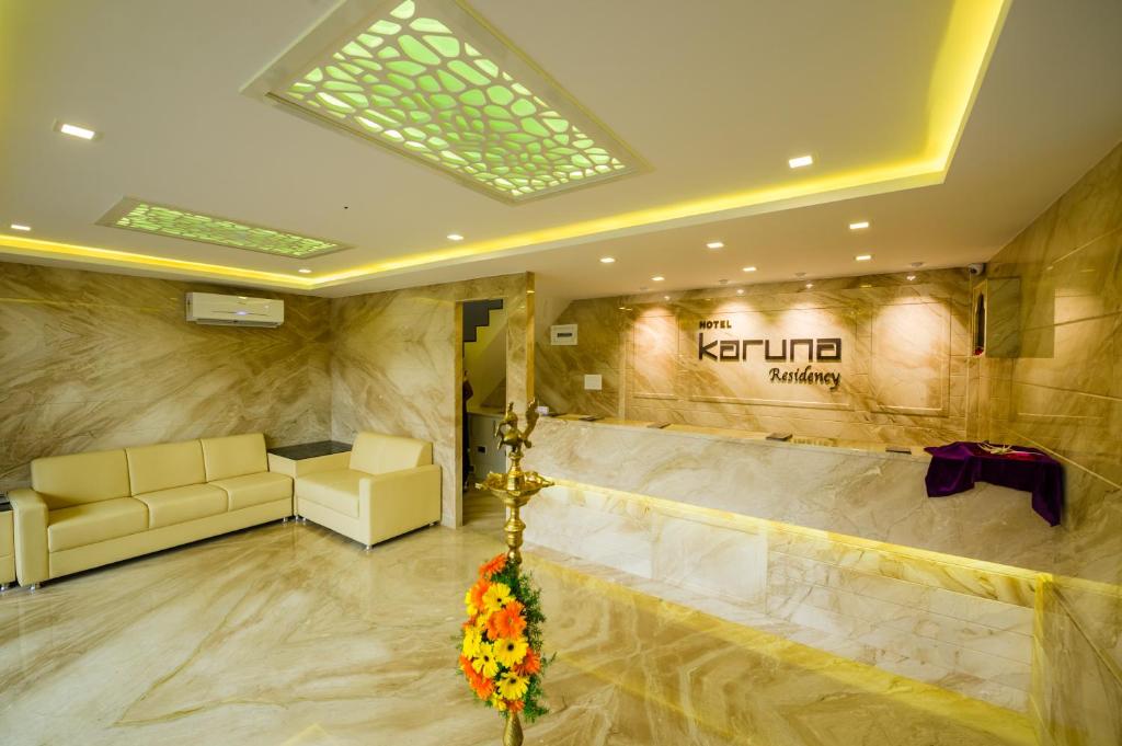a lobby with a waiting room with couches and flowers at Hotel Karuna Residency in Mangalore