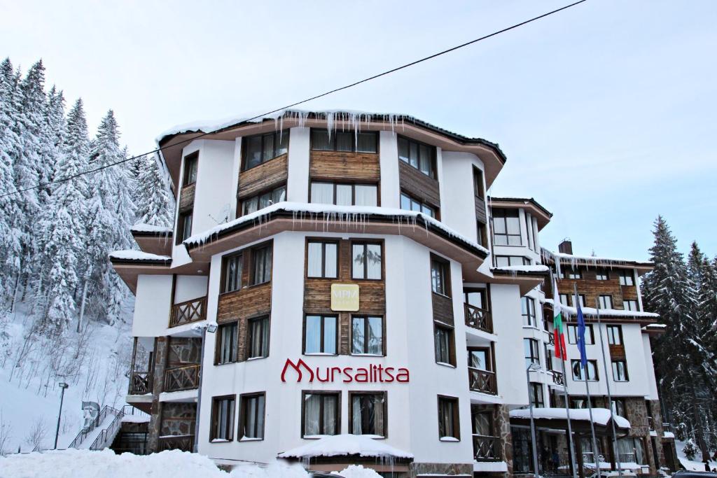 Ein Gebäude mit einem Schild im Schnee. in der Unterkunft Hotel Mursalitsa by HMG in Pamporowo
