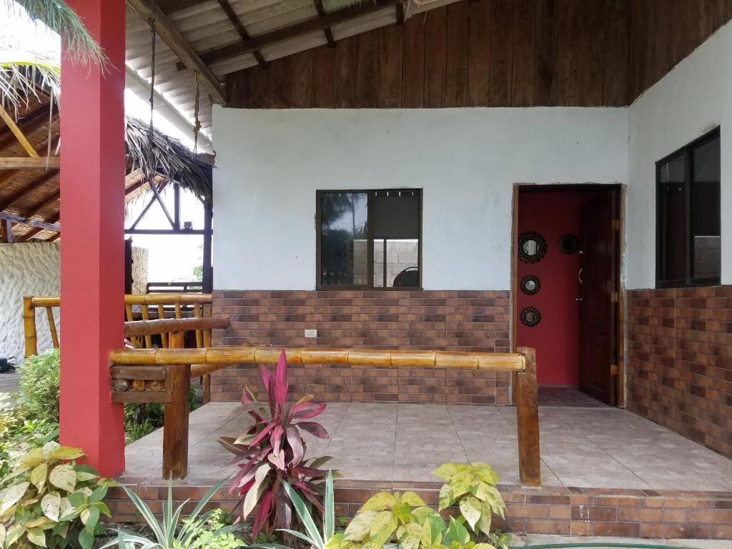 un banco de madera en un edificio con puerta roja en Hugo's Relax Home (Casa), en Ayangue