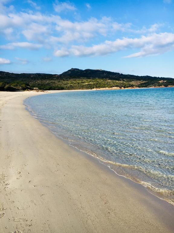 a sandy beach with water and mountains in the background at Hotel Les Chambres de Mila Bonifacio in Bonifacio