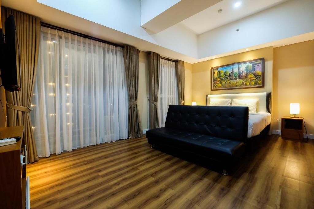 une chambre d'hôtel avec un canapé et un lit dans l'établissement Exclusive 1BR Casa De Parco Apartment near AEON Mall By Travelio, à Tangerang
