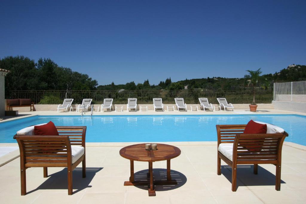 2 sillas y una mesa junto a la piscina en Lagrange Vacances Le Domaine de Bourgeac en Paradou