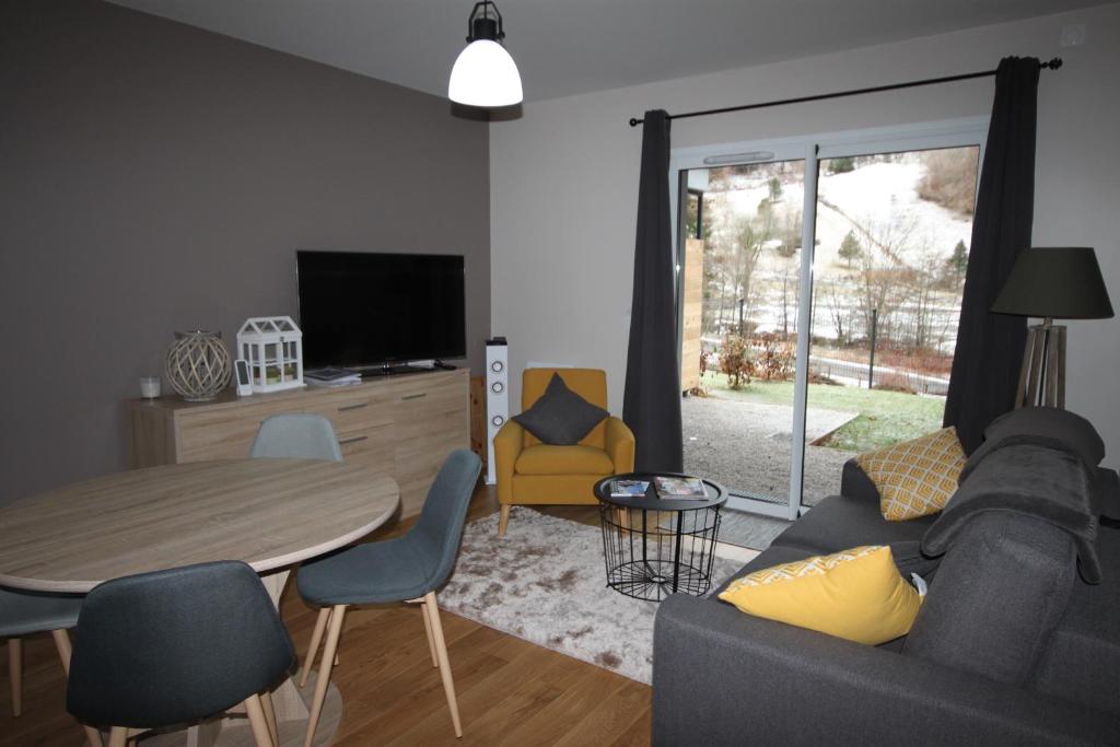 a living room with a couch and a table and chairs at A1 - Résidence La Montille in Le Mont-Dore