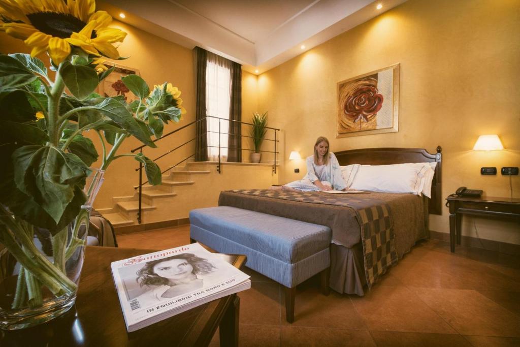 a woman sitting on a bed in a hotel room at Artemis Hotel in Cefalù