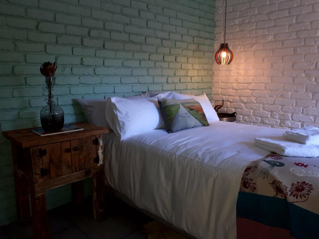 a bed with white sheets and a lamp on a table at Oppermans Villa in Pretoria