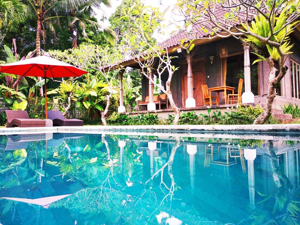 een huis met een parasol en een zwembad bij Thani Villa in Ubud