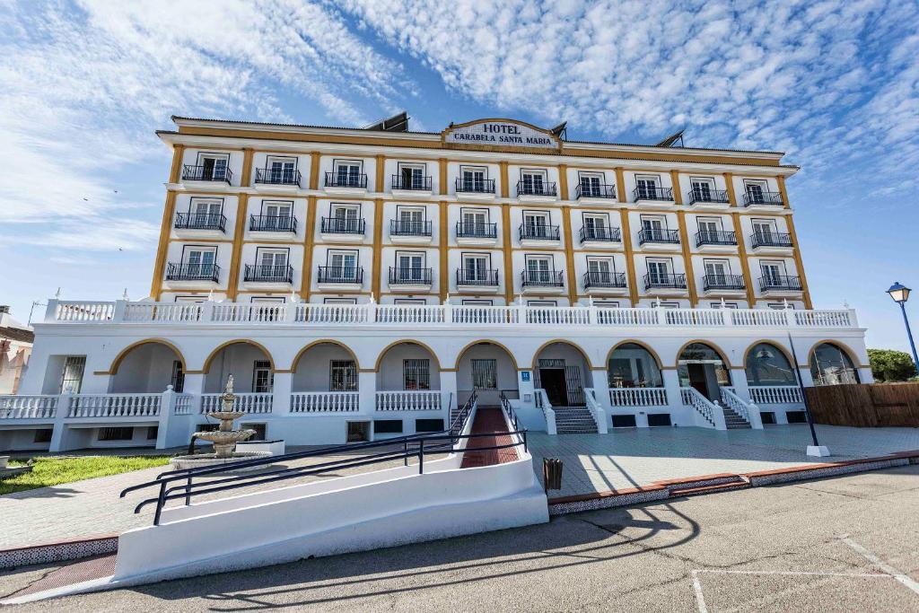 un grand bâtiment jaune et blanc avec un ciel dans l'établissement Hotel Carabela Santa María, à Mazagón