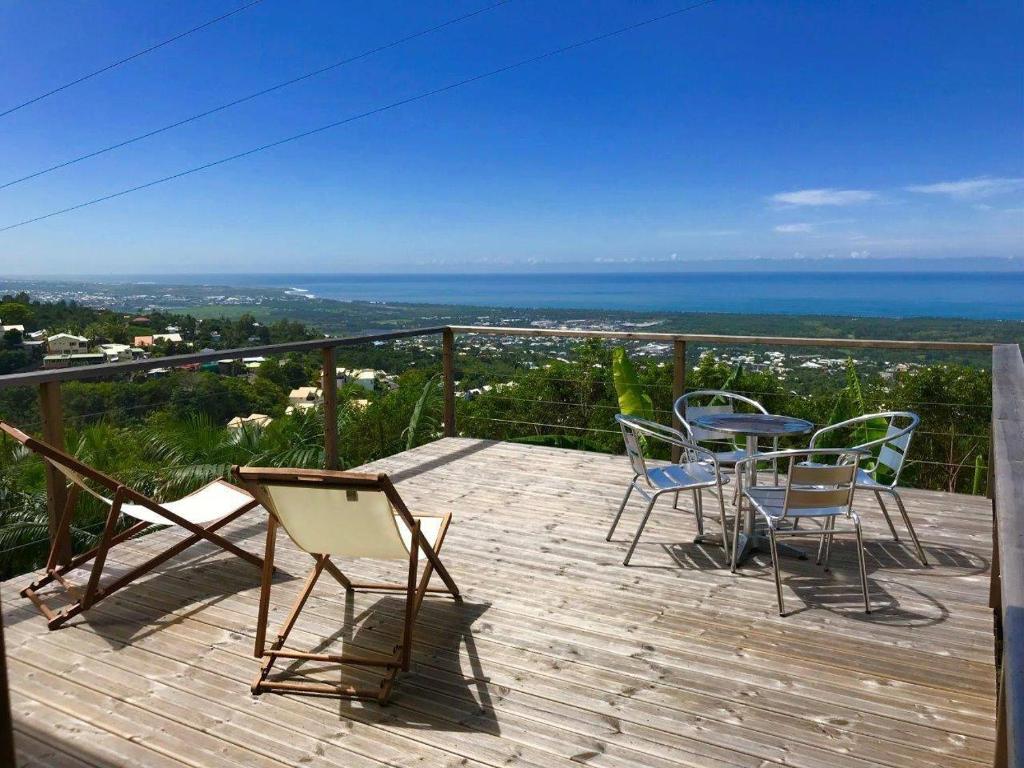 une terrasse avec des chaises et une table et une vue sur l'océan dans l'établissement Lounge des hauts 3 maisons à L'étang-Salé sans vis à vis avec vue panoramique Océan et Montagne, à L'Étang-Salé