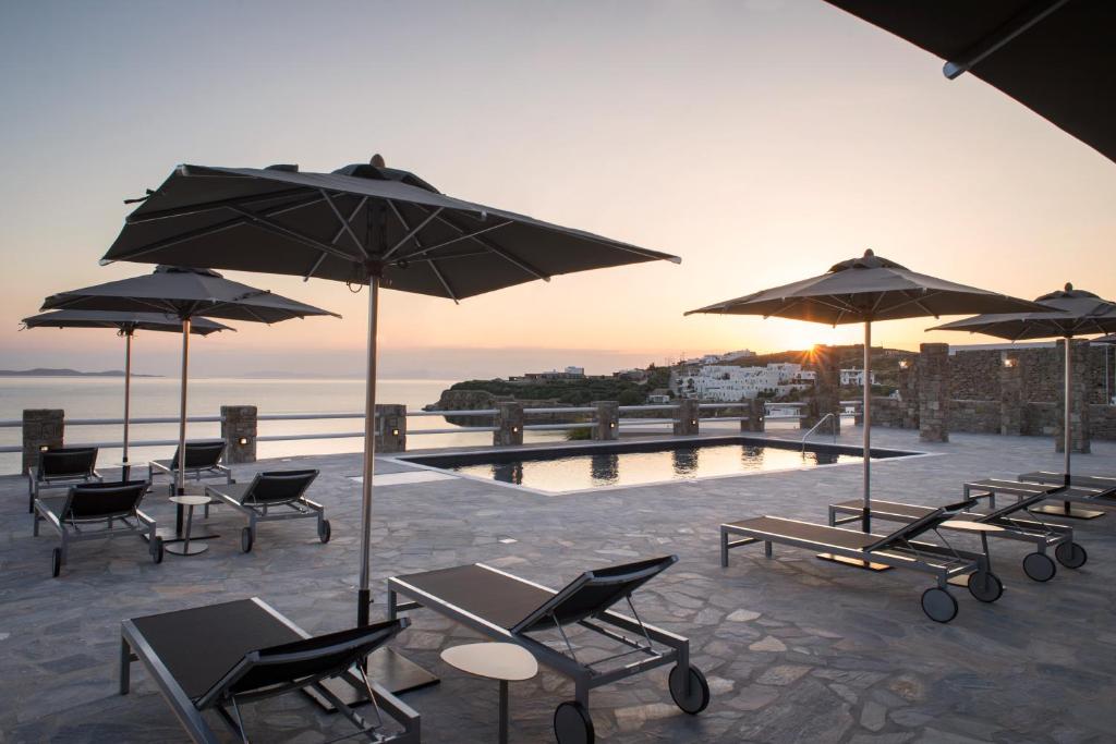 a group of chairs and umbrellas next to a pool at Alkistis Beach Hotel - Adults Only in Agios Stefanos