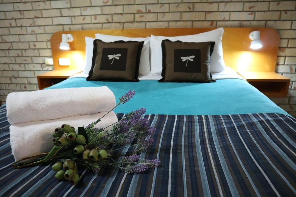 ein Schlafzimmer mit einem Bett mit einer blauen Bettdecke und Kissen in der Unterkunft Kilcoy Gardens Motel in Kilcoy