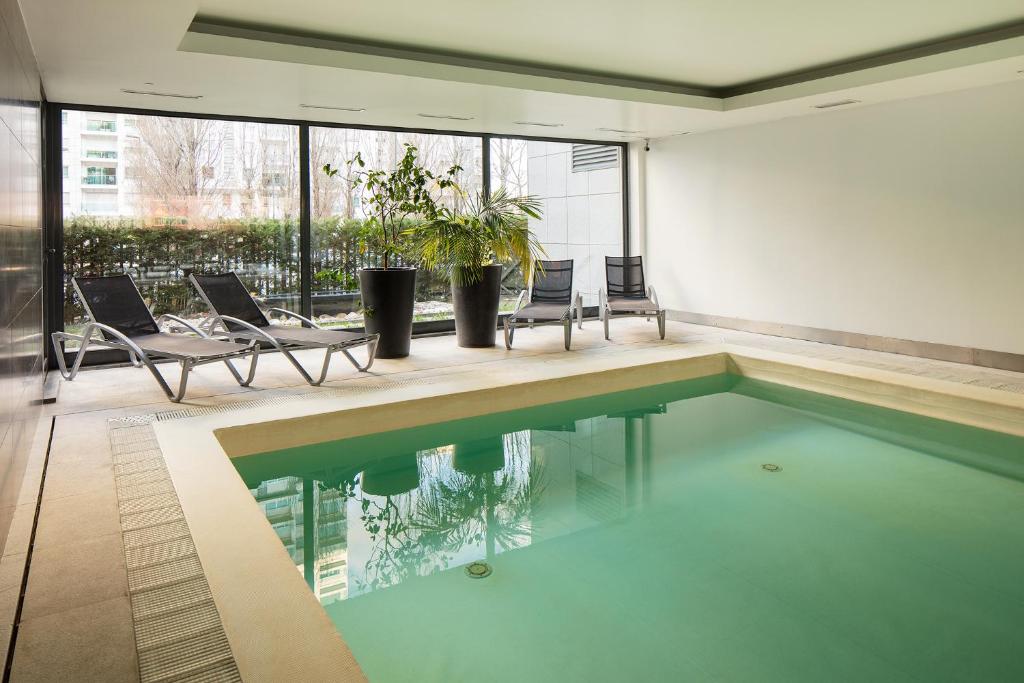 a swimming pool in a house with chairs and windows at Skyscraper Riverview Lisbon with Indoor Pool in Lisbon