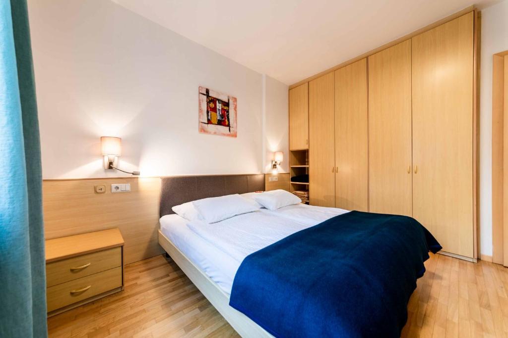 a bedroom with a large bed with a blue blanket at Pixner Apartments in Bolzano