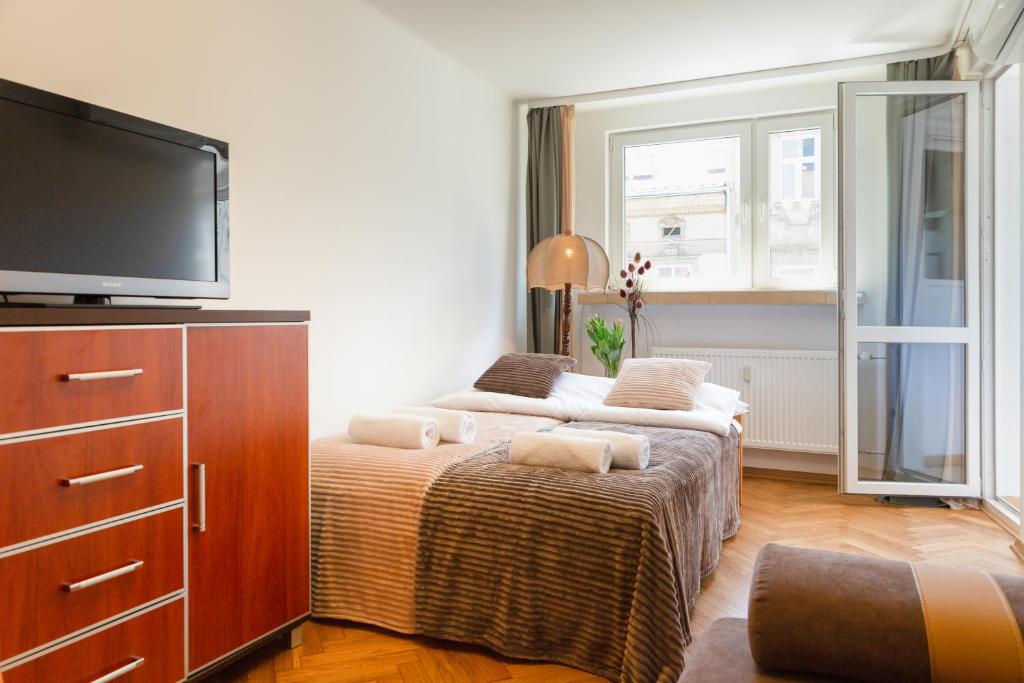 a bedroom with two beds and a flat screen tv at Traditional Apartment Starowiślna street in Krakow