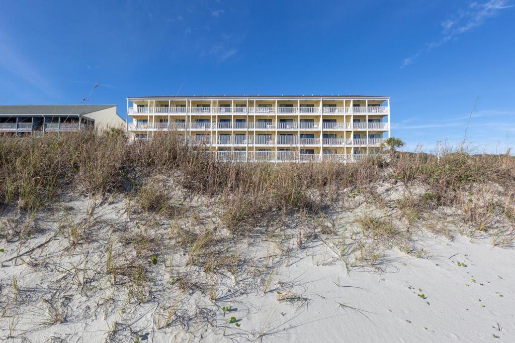 a building on top of a beach with grass and sand at Windy Shores II in Myrtle Beach