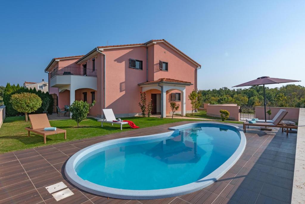 a villa with a swimming pool in front of a house at Ferienhaus Joy in Ližnjan