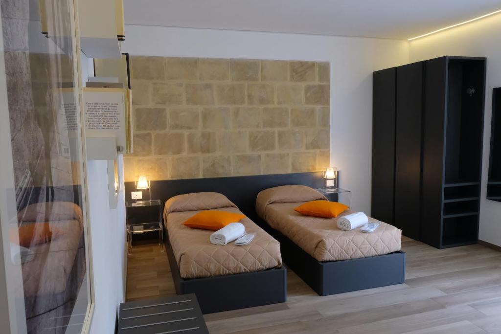 2 bedden met oranje kussens in een kleine kamer bij Locanda Degli Scrittori in Agrigento