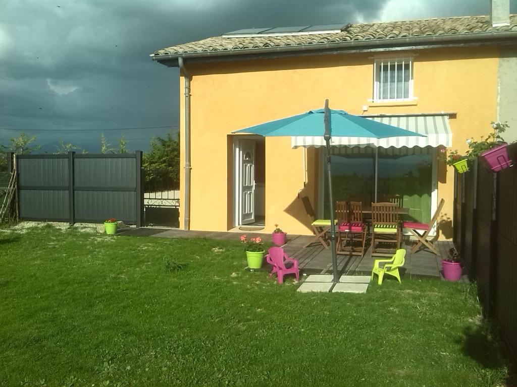 a backyard with a table and chairs and an umbrella at GITE LA CLE DES CHAMPS in Chabeuil