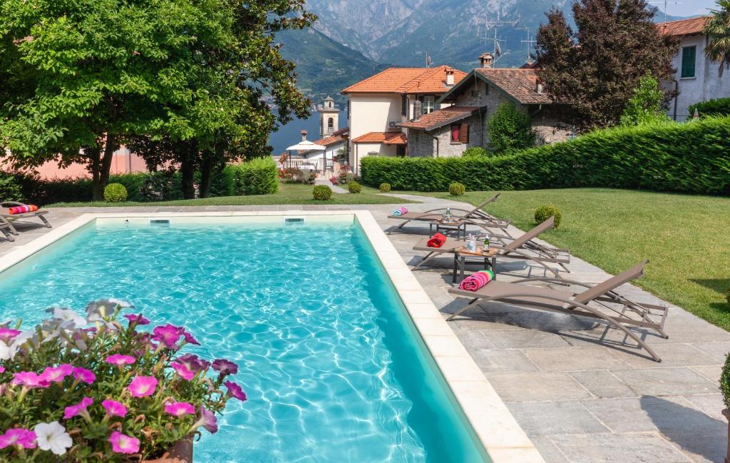 a swimming pool with chairs and flowers in a yard at Villa La Dolce Vita in Oliveto Lario