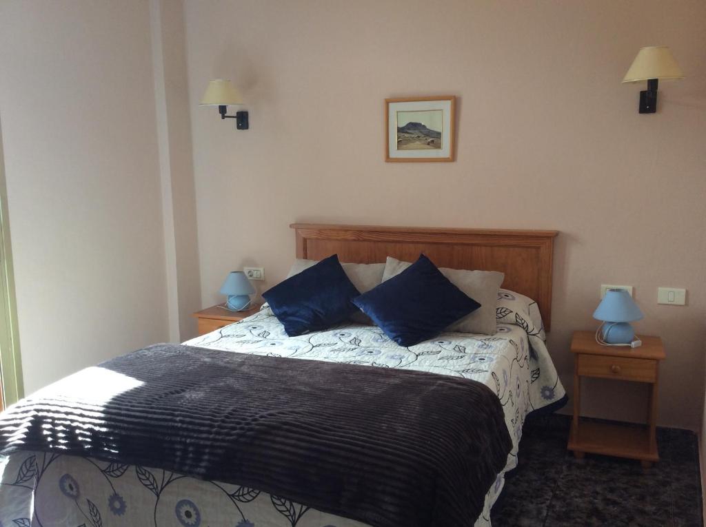a bedroom with a large bed with blue pillows at Hotel Sonia Chipude in El Cercado