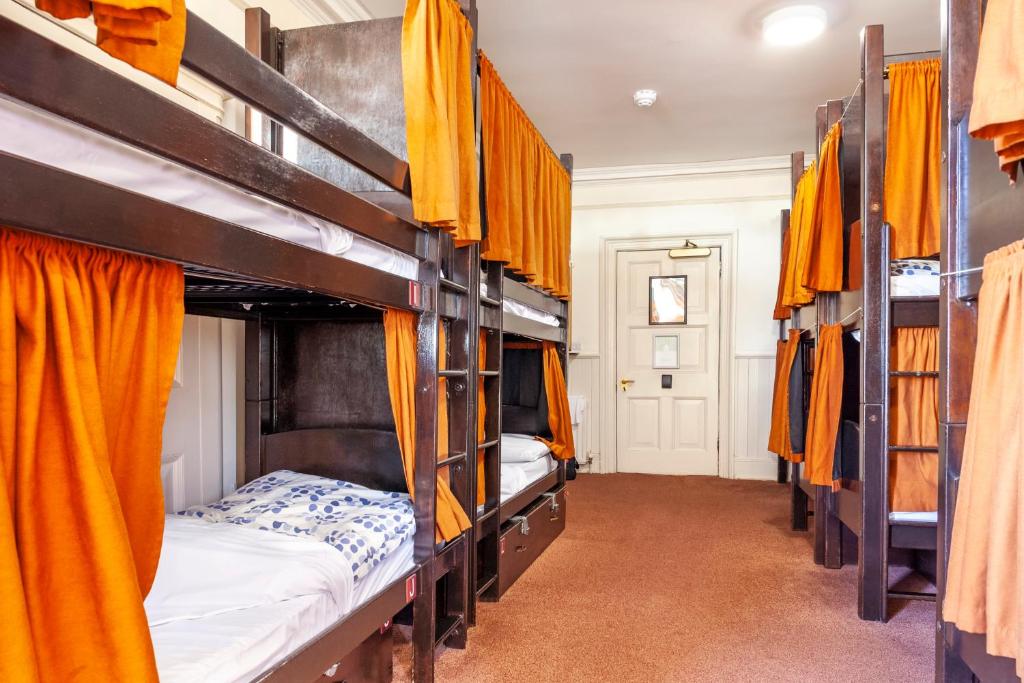 a room with four bunk beds with orange curtains at Palmers Lodge Swiss Cottage in London