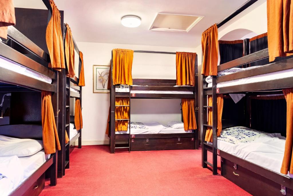a room with four bunk beds with orange curtains at Palmers Lodge Swiss Cottage in London